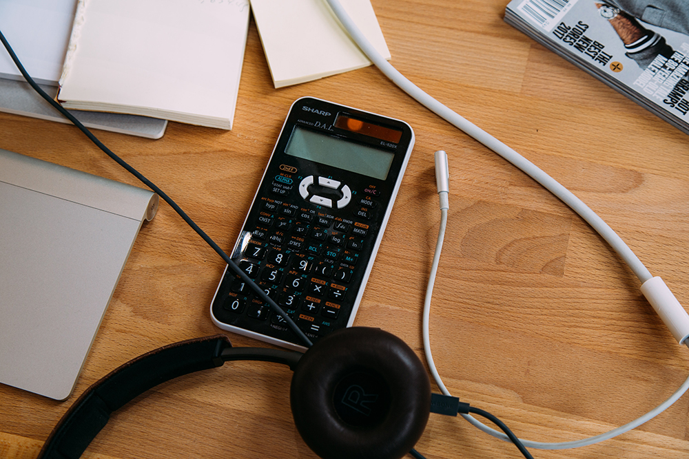 Calculator on a desk with pads of paper. 